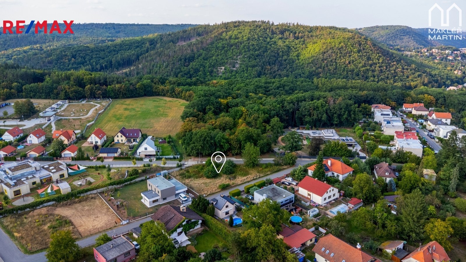 Pozemek pro bydlení v Černošicích, letecký pohled na zástavbu a les